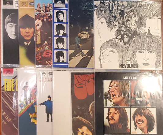Collection of The Beatles' album covers displayed on a wooden frame.